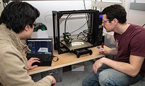 Engineering students work with a 3D printer