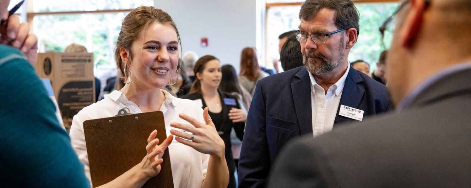 Dr. Gary Karns looks on as an SPU student does her presentation at the annual Social Venture Competition Showcase.